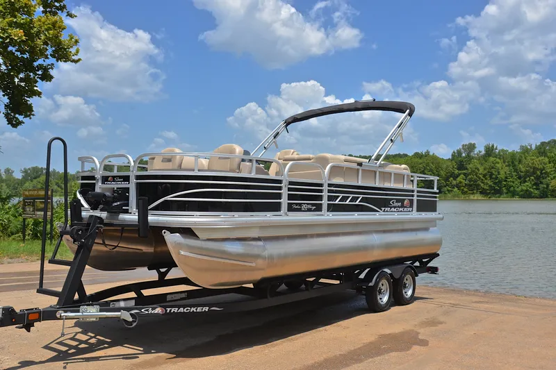 Slide: The Image of 2022 Sun Tracker Fishin' Barge 20 DLX pontoon boat on trailer by a lake. - 9