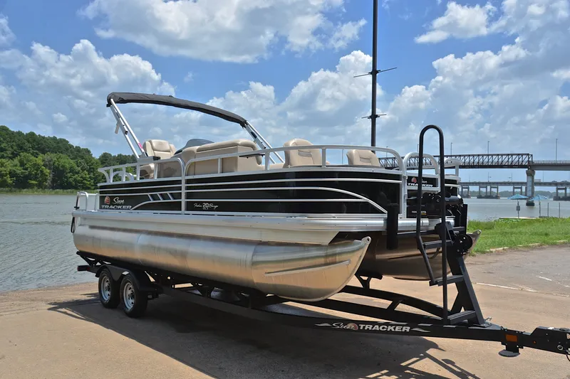 Slide: The Image of 2022 Sun Tracker Fishin' Barge 20 DLX pontoon boat on trailer by a lake. - 16