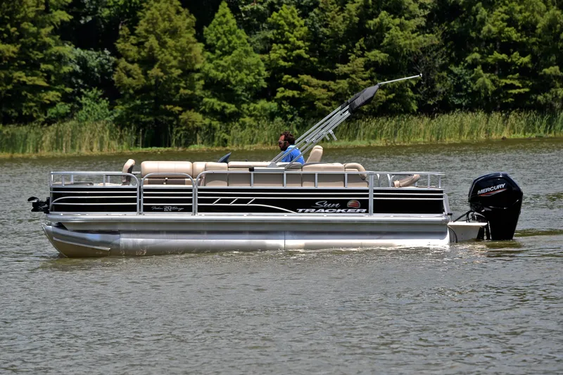 Slide: The Image of 2022 Sun Tracker Fishin' Barge 20 DLX pontoon boat cruising on a serene lake. - 10