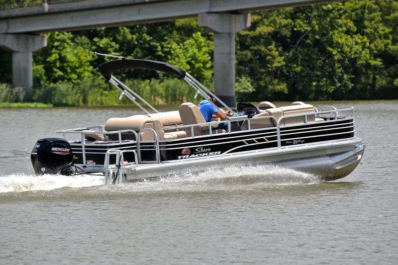 Slide: The Image of 2022 Sun Tracker Fishin' Barge 20 DLX pontoon boat cruising on a lake. - 5