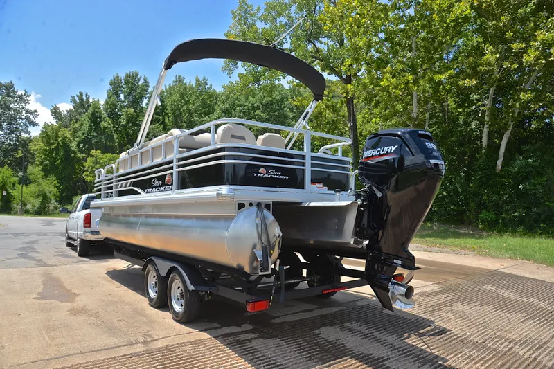 Slide: The Image of 2022 Sun Tracker Fishin' Barge 20 DLX on trailer, parked near lush green trees. - 12