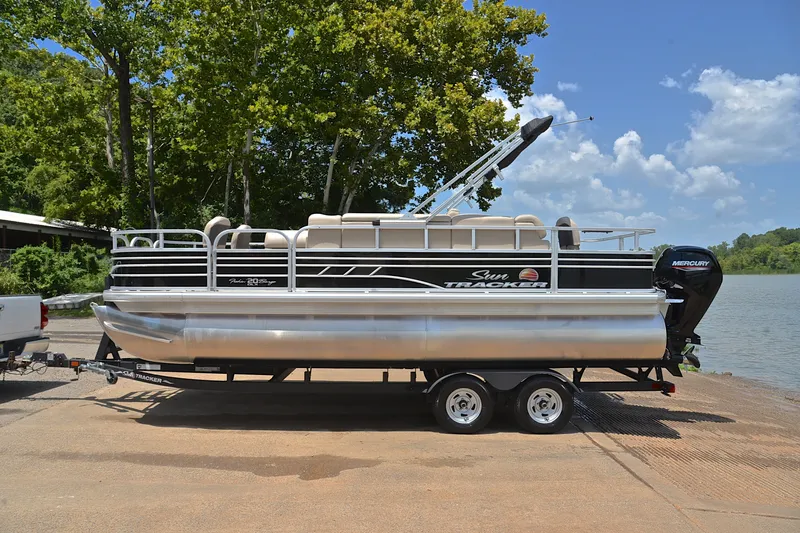 Slide: The Image of 2022 Sun Tracker Fishin' Barge 20 DLX pontoon boat on trailer by a lake. - 11