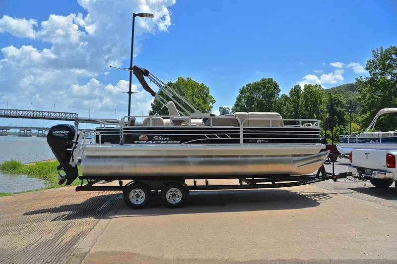 Slide: The Image of 2022 Sun Tracker Fishin' Barge 20 DLX pontoon boat on trailer by a lake. - 15
