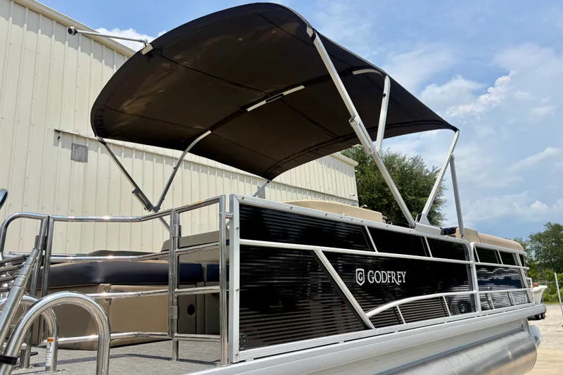 Slide: The Image of 2023 Sweetwater 2286 FSL pontoon boat with canopy, docked near a building. - 11