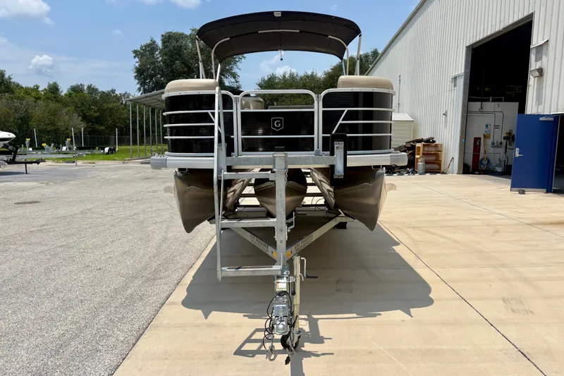 Slide: The Image of 2023 Sweetwater 2286 FSL pontoon boat on trailer, parked outside a warehouse. - 13