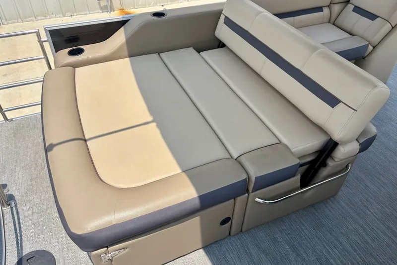 Slide: The Image of 2023 Sweetwater 2286 FSL boat with beige and gray seating, featuring cup holders and storage. - 22