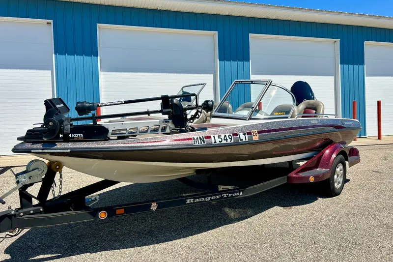 The Image of 2006 Ranger 180 Reata boat on trailer, parked outside blue building. - 1