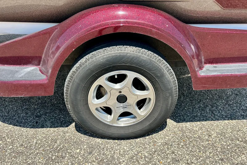Slide: The Image of Trailer wheel of a 2006 Ranger 180 Reata boat, featuring a maroon fender. - 54