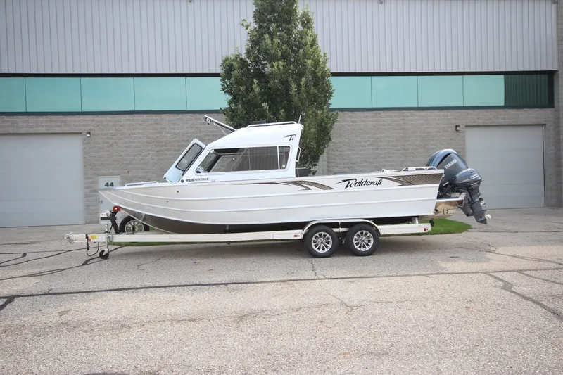 The Image of 2027 Weldcraft 240 Maverick DV boat on trailer, parked outside industrial building. - 0