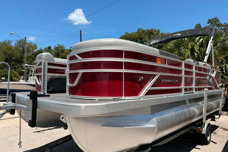 The Image of 2024 Bennington SV 20 pontoon boat with red exterior, parked on a trailer. - 0
