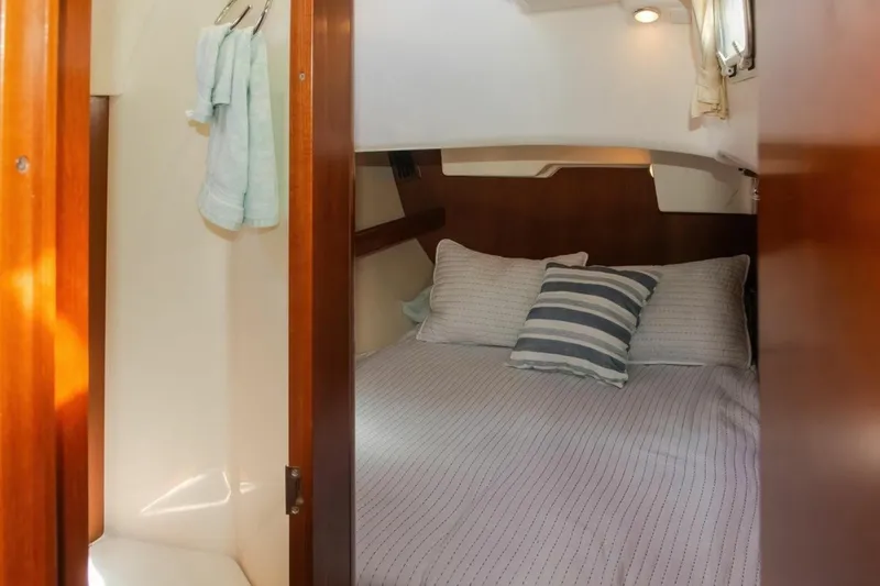 Slide: The Image of Cozy cabin interior of 2007 Beneteau Oceanis Clipper 523 with striped bedding and wooden accents. - 25