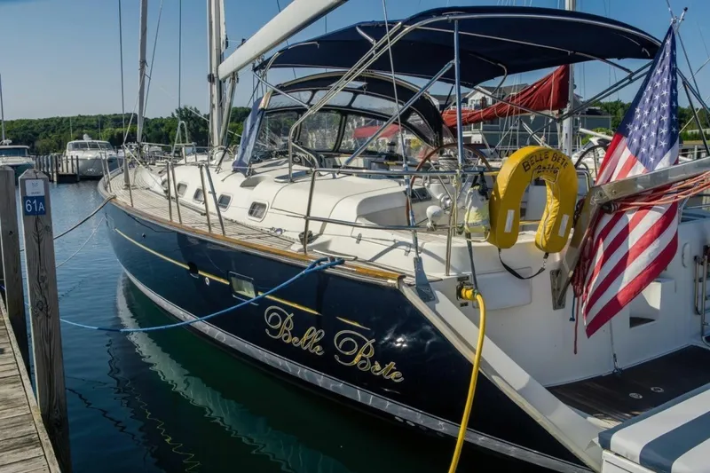 Slide: The Image of 2007 Beneteau Oceanis Clipper 523 sailboat docked, featuring navy hull and American flag. - 1