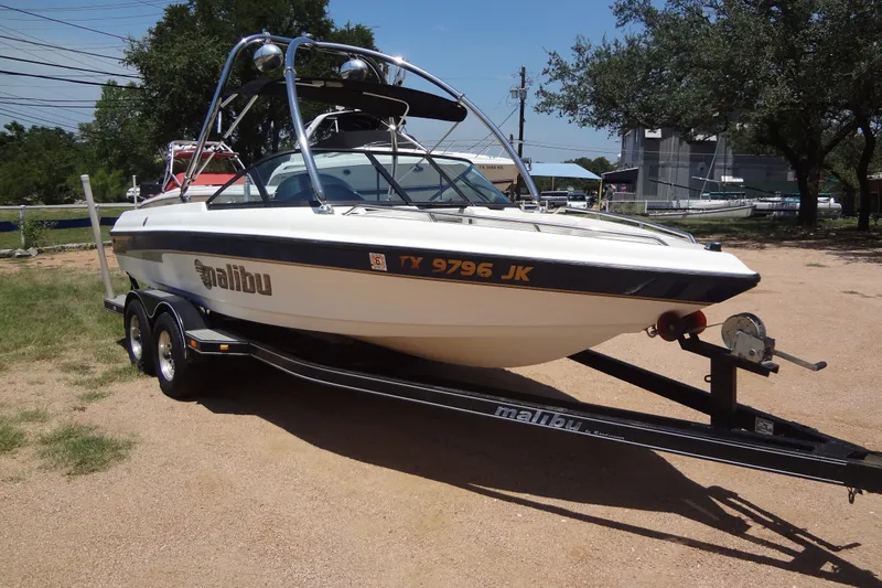 The Image of 2000 Malibu Sunsetter VLX boat on trailer, parked outdoors on a sunny day. - 0