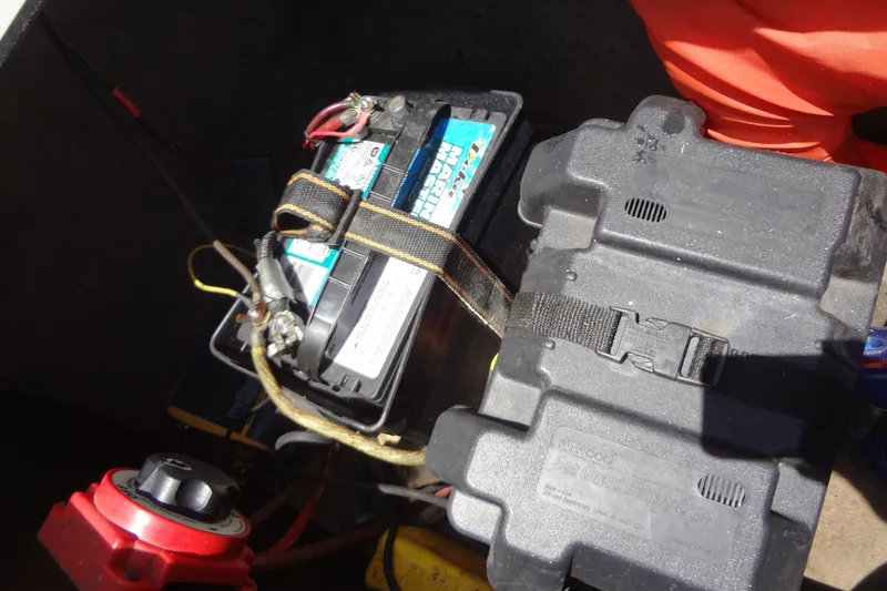 Slide: The Image of Battery compartment of a 2000 Malibu Sunsetter VLX boat with secured battery and cables. - 29