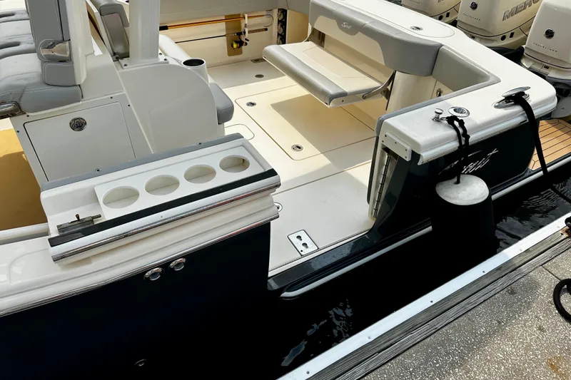 Slide: The Image of 2019 Scout 355 LXF boat interior with seating and cup holders at dock. - 18