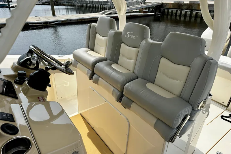 Slide: The Image of 2019 Scout 355 LXF boat interior with luxurious seating and steering wheel at the dock. - 10