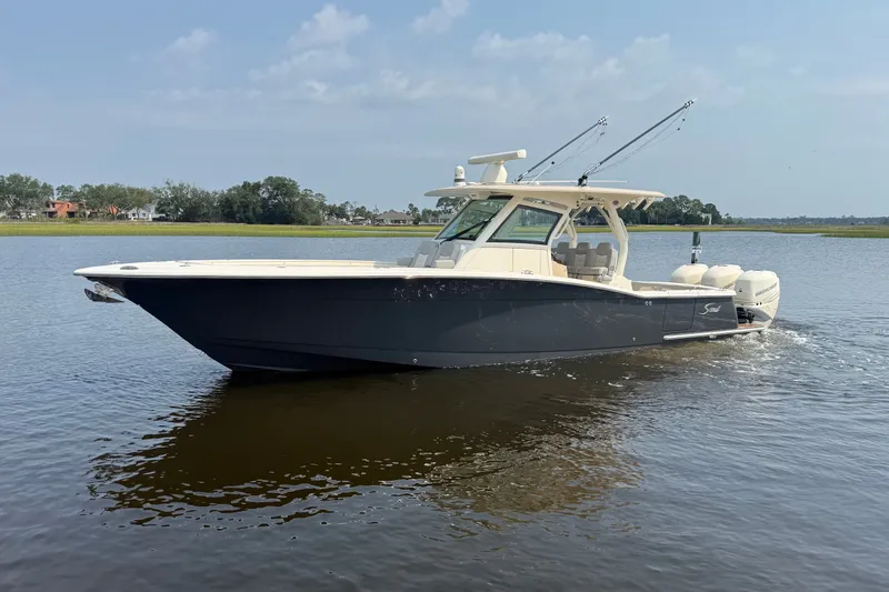 The Image of 2019 Scout 355 LXF boat cruising on calm water under a clear sky. - 0