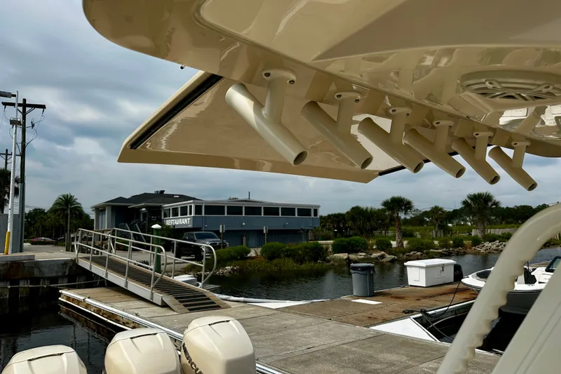 Slide: The Image of 2019 Scout 355 LXF boat docked near waterfront restaurant, showcasing rod holders. - 17