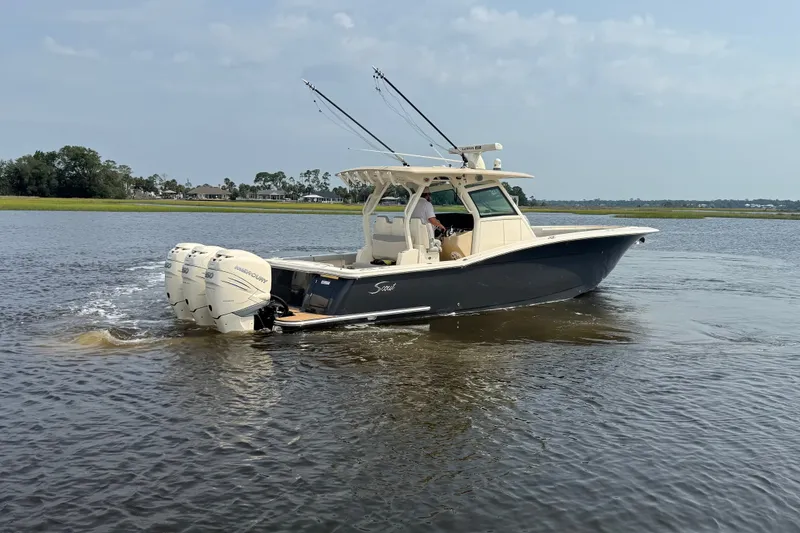 Slide: The Image of 2019 Scout 355 LXF boat cruising on a calm river with triple outboard engines. - 5