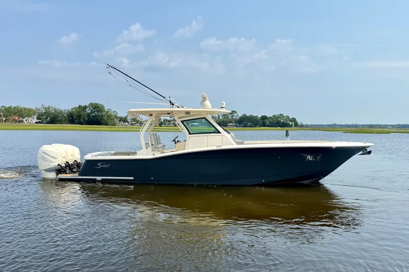 Slide: The Image of 2019 Scout 355 LXF boat cruising on a calm lake under a clear blue sky. - 4