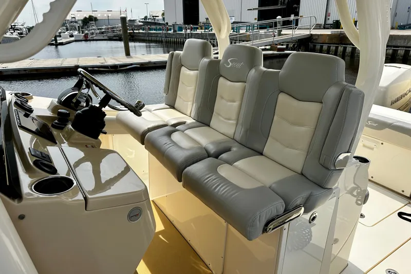 Slide: The Image of 2019 Scout 355 LXF boat interior with luxurious seating and steering console at marina. - 9