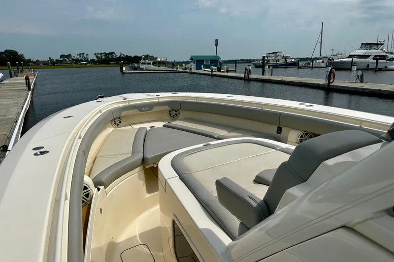 Slide: The Image of 2019 Scout 355 LXF boat with luxurious seating at a marina dock. - 19