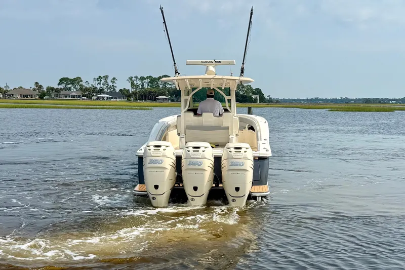 Slide: The Image of 2019 Scout 355 LXF boat with triple Yamaha 350 engines on a calm waterway. - 6