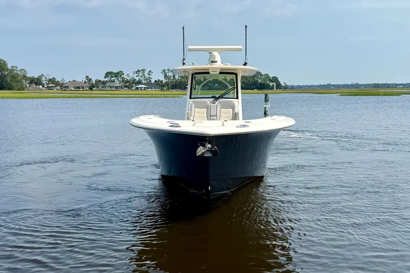 Slide: The Image of 2019 Scout 355 LXF boat on calm water, front view with scenic background. - 2