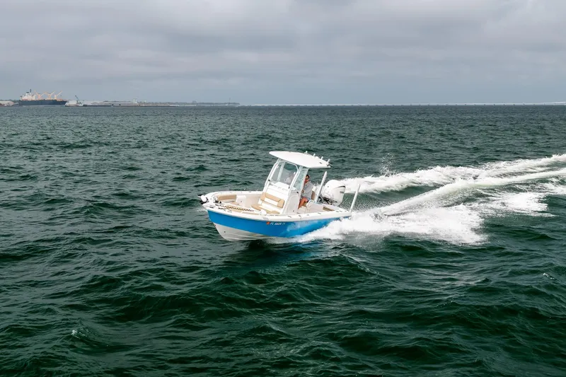 Slide: The Image of 2023 Everglades 243 Center Console boat cruising on open water under cloudy skies. - 63