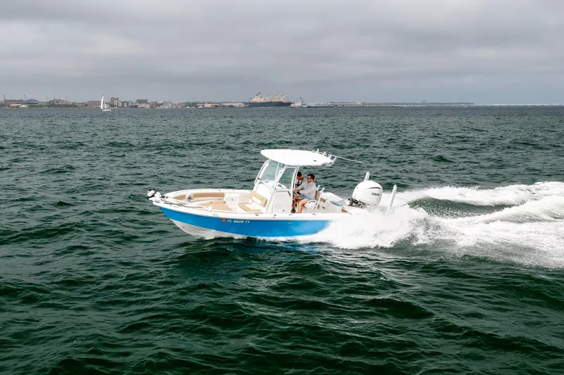 Slide: The Image of 2023 Everglades 243 Center Console boat cruising on open water under cloudy skies. - 62