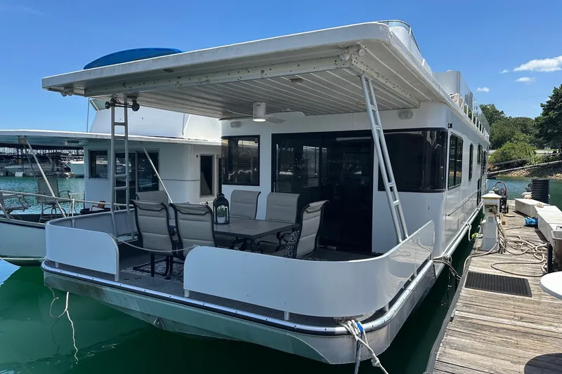 The Image of 1993 Sumerset 14x65 houseboat docked, featuring spacious deck and outdoor seating. - 0