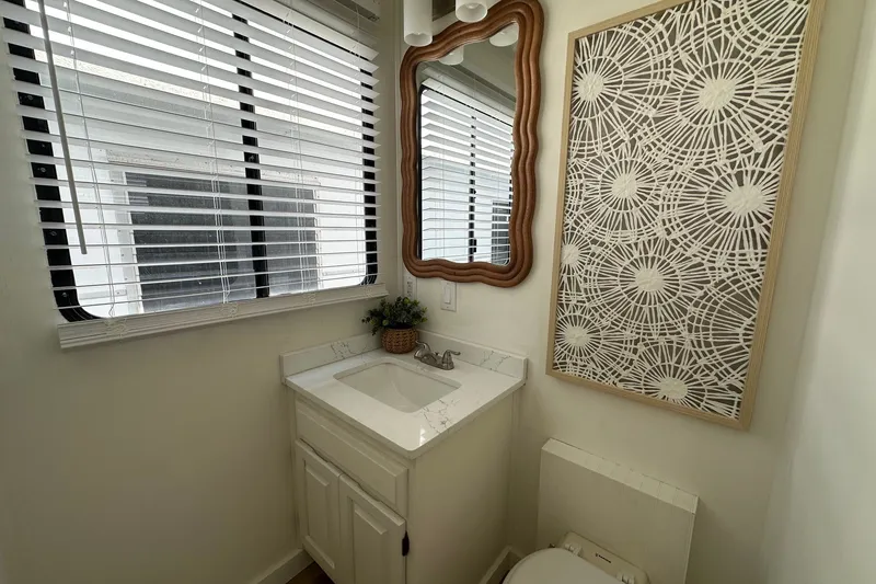 Slide: The Image of Small bathroom with decorative mirror, patterned wall art, and window blinds in a 1993 Sumerset 14x65. - 8
