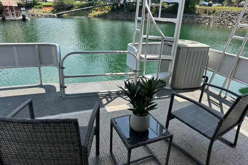 Slide: The Image of Deck of 1993 Sumerset 14x65 houseboat with chairs, table, and potted plant by the water. - 12