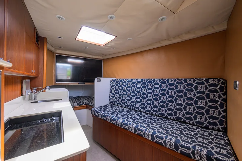 Slide: The Image of Interior of 2014 Release Boatworks 46, featuring a kitchenette, patterned seating, and a flat-screen TV. - 45