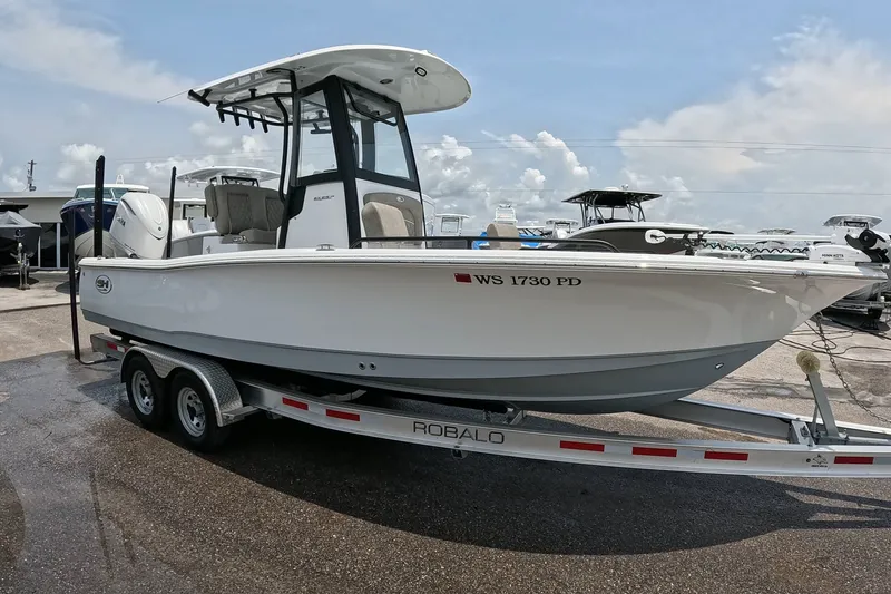 Slide: The Image of 2026 Seahunt BX25FS boat on trailer, parked outdoors under a cloudy sky. - 2