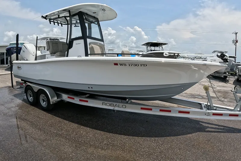 The Image of 2026 Seahunt BX25FS boat on a Robalo trailer, parked outdoors. - 1