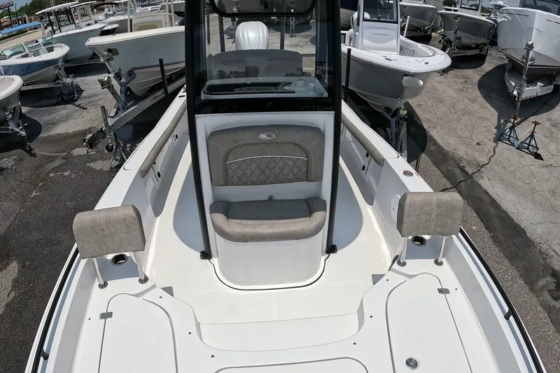 Slide: The Image of 2026 Seahunt BX25FS boat interior with cushioned seating, surrounded by other boats in a marina. - 19
