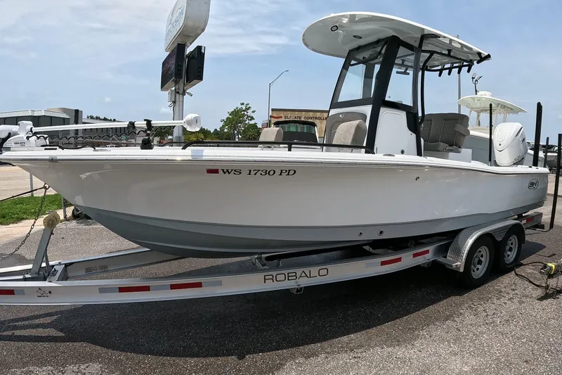 Slide: The Image of 2026 Seahunt BX25FS boat on a Robalo trailer, parked outdoors. - 3