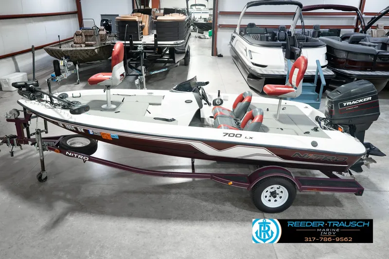 The Image of 1998 Nitro 700 LX SC fishing boat on trailer in showroom, featuring Tracker outboard motor. - 0