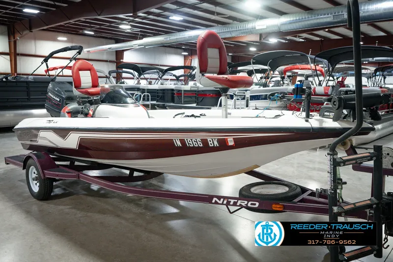 Slide: The Image of 1998 Nitro 700 LX SC boat on trailer in indoor showroom, featuring red and white seating. - 4