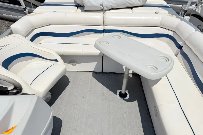 Slide: The Image of Interior of a 2001 Harris Cruiser 220 boat with white seating and a small table. - 8