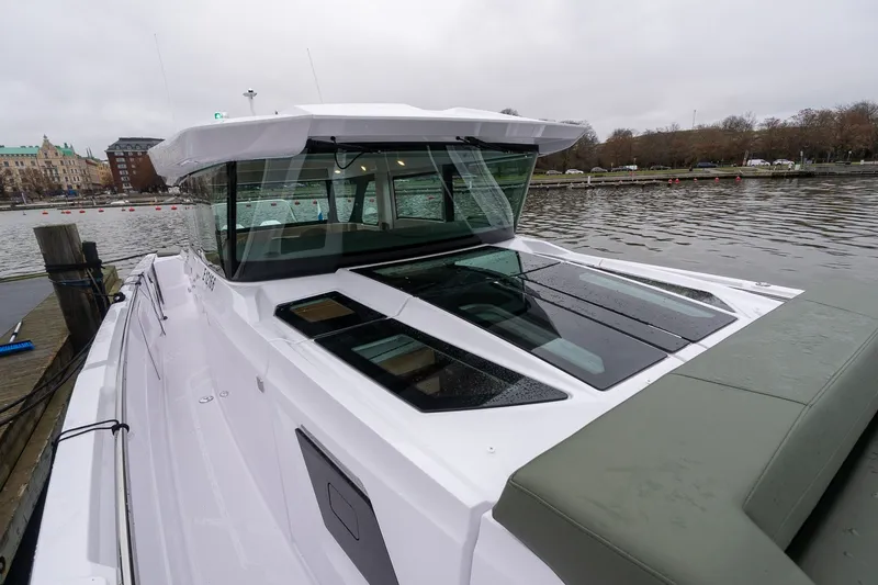 Slide: The Image of 2027 Axopar 38 Cross Cabin boat docked by a calm waterfront. - 29