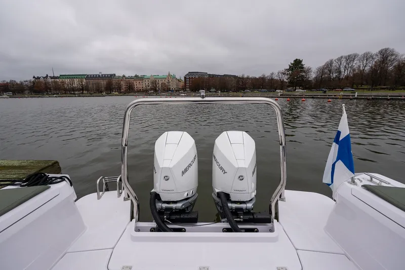 Slide: The Image of 2027 Axopar 38 Cross Cabin with dual Mercury engines, docked by a scenic waterfront. - 13