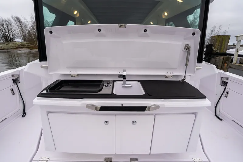 Slide: The Image of 2027 Axopar 38 Cross Cabin boat kitchen with sink and storage compartments. - 7