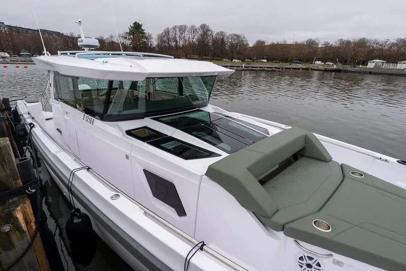 Slide: The Image of 2027 Axopar 38 Cross Cabin boat docked by a calm waterfront. - 4