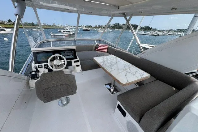 Slide: The Image of 2023 Azimut Fly 50 yacht interior with helm, seating, and table, overlooking marina. - 40