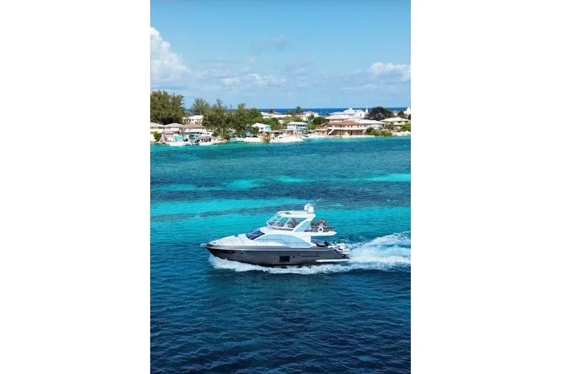 Slide: The Image of 2023 Azimut Fly 50 yacht cruising on vibrant blue waters near a coastal town. - 0