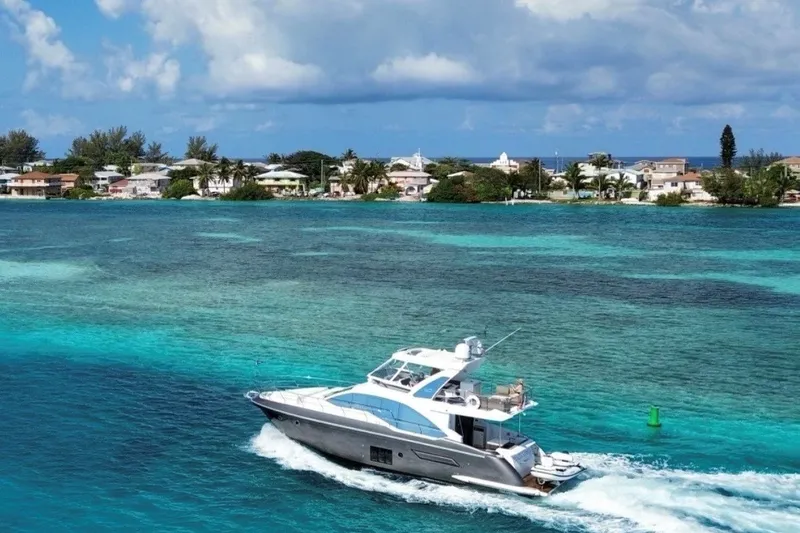 Slide: The Image of 2023 Azimut Fly 50 yacht cruising in turquoise waters near a coastal town. - 3