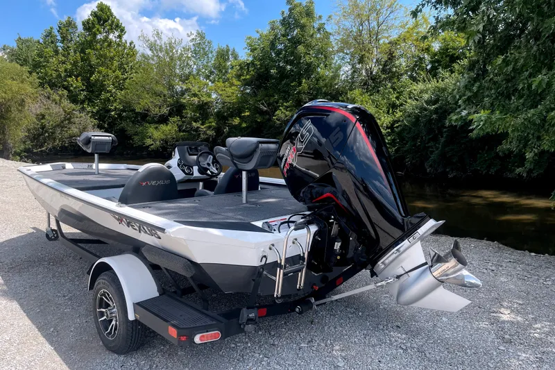 Slide: The Image of A 2023 Vexus AVX189C boat on a trailer beside a river, surrounded by trees. - 4