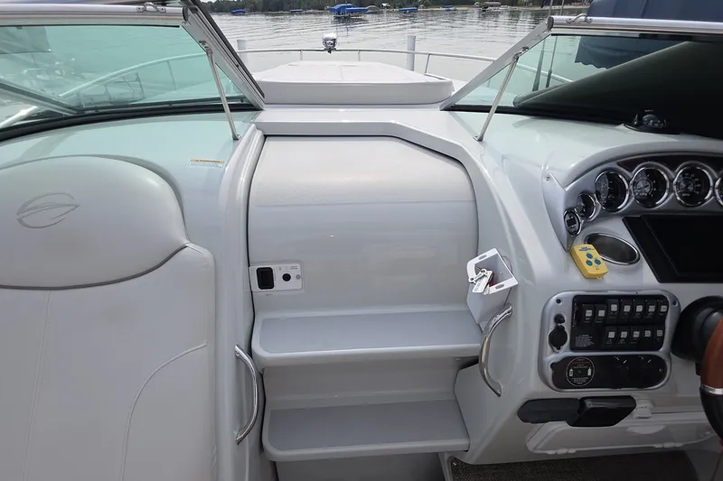 Slide: The Image of 2017 Crownline 325 SCR helm with controls, gauges, and seating, docked by the water. - 13